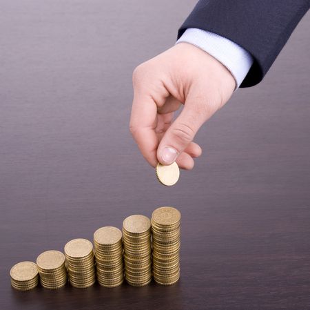 Hand put coin to money staircase on wood desk