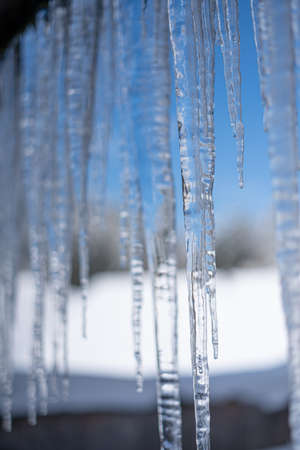 Cold temperatures causing icicles in winter . Blurred Background behind the iciclesの写真素材
