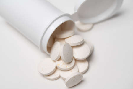 White pills and white container isolated. Medicine for sickness and health problems. Drugs and...