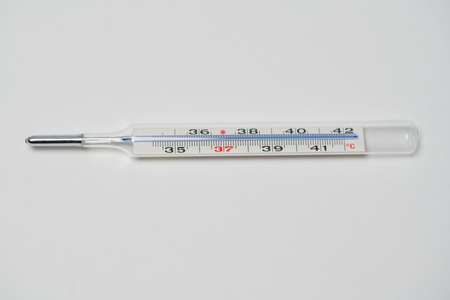 Mercury in glass thermometer on white surface. Copyspace on top and bottom. Fever thermometer in...
