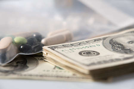Dollar Bills and Pills. Drugs in plastic bag with cash money. Illegal Drugs in package. 100 Dollar...