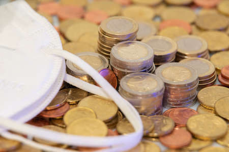 N95 Surgical mask on pile of Euro Coins and Money. Cost of Masks, protection of Virus.