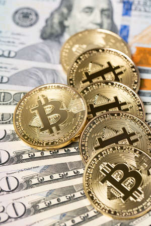 Bitcoin piled up on fifty and one hundred dollar banknotes. Crypto currency and paper money exchange...