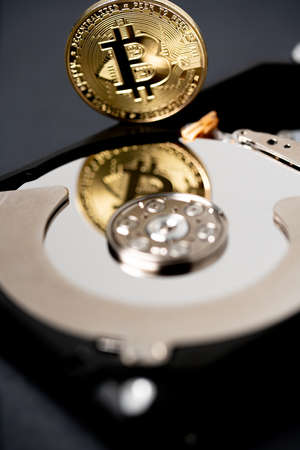 Gold bitcoin reflecting on hard drive platter of hard disk storage. Digital crypto currency and blockchain technology conceptの写真素材