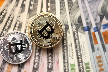 Piled up bitcoin coins on top of US dollar banknotes. Gold and silver BTC coins. Crypto exchange to...