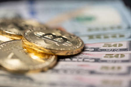 Closeup bitcoins on fifty dollar bills. Purchase with digital currency or paper money. US dollar...