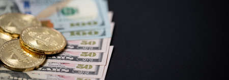 Closeup bitcoins on fifty dollar bills. Purchase with digital currency or paper money. US dollar...