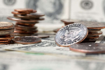 Piled up dollar coins on one dollar banknotes. US dollar cash, paying bills and tipping. Investing...
