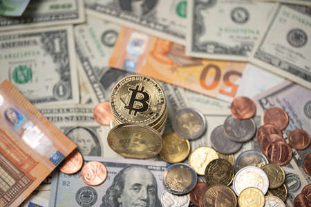 Bitcoins piled up on top of dollar and euro banknotes. Gold BTC coins with dollar coins, trading...