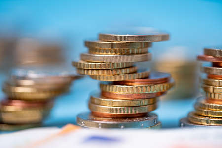 Piled up euro coins with blue background. Banknotes in front out of focus. European monetary union...