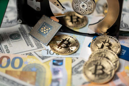 Crypto mining concept, bitcoin reflecting in hard drive disk next to US dollar banknotes and euro...