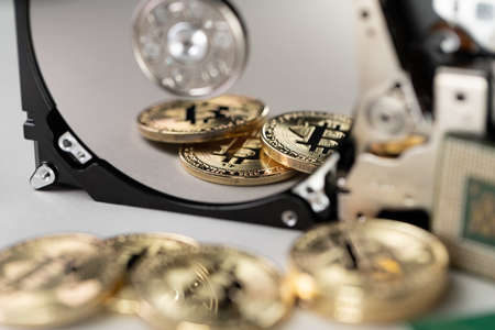 Bitcoin coins reflecting on hard drive disk. Concept of saving cryptocurrency transactionの写真素材