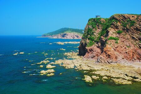 Cliff at sea shore with rocks and island. の写真素材
