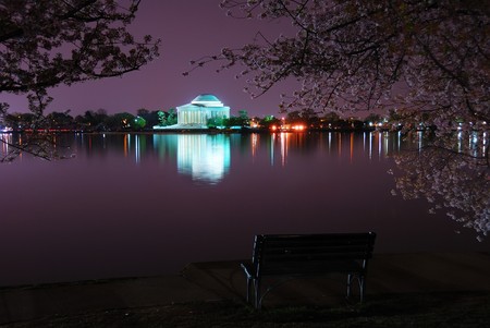 Thomas Jefferson Memorial illuminated with light with cherry blossom and chair by lake. Washington DC.のeditorial素材