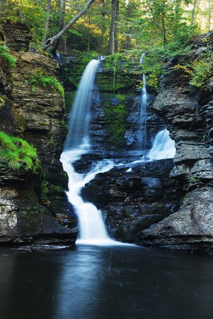 Waterfall in woods in Autumn with rocks in mountainの写真素材