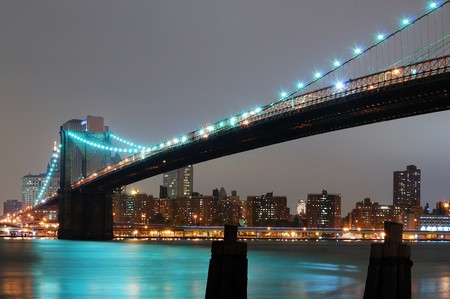 New York City with Brooklyn Bridge at night over Hudson River.の写真素材