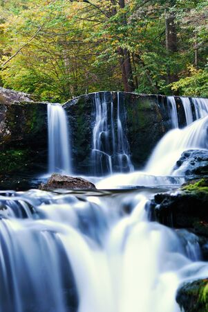 Waterfall over rocks in mountain forest with trees in Autumn. の写真素材