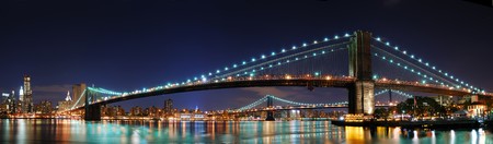 New York City Manhattan skyline panorama with Brooklyn Bridge and office skyscrapers building in at dusk illuminated with lights at nightの写真素材