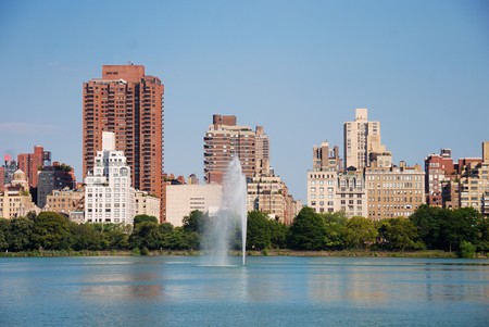 New York City Central Park fountain and urban Manhattan skyline with skyscrapers and trees lake reflection with blue sky and white cloud.の写真素材