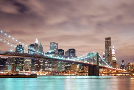 New York City Manhattan panorama view with Brooklyn Bridge at night with office building skyscrapers skyline illuminated over Hudson Riveの写真素材