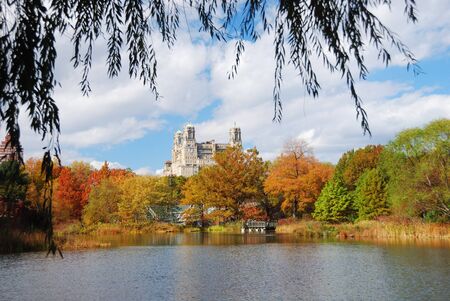 New York City Central Park in Autumn with Manhattan skyscrapers and colorful trees over lake with reflection.の写真素材