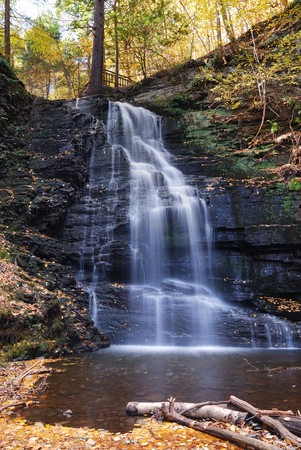 Waterfall in mountain with Autumn foliage and woods over rocks.の写真素材
