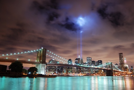 New York City Manhattan panorama view with Brooklyn Bridge at night with office building skyscrapers skyline illuminated over Hudson River.の写真素材