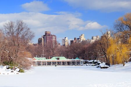 New York City Manhattan Central Park panorama in winter with ice and snow over lake with skyscrapers and blue sunny sky at dusk.の写真素材