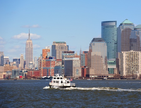 Urban skyscrapers and boat from New York City Manhattan downtown over river.の写真素材