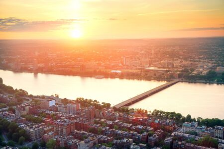 Boston Charles River sunset aerial view with urban buildings and bridge.