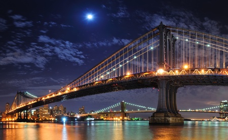 Brooklyn Bridge and Manhattan Bridge over East River at night with moon in New York City Manhattan with lights and reflections.の写真素材