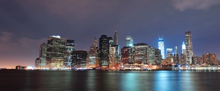 New York City Manhattan downtown skyline with skyscraper and water reflection over East River at nightの写真素材