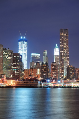 New York City Manhattan downtown urban skyscraper closeup over East River at night with light reflection.の写真素材