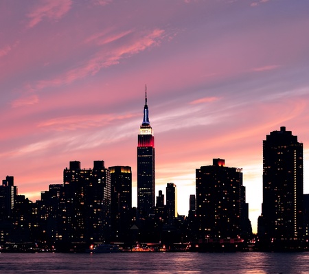 New York City Manhattan midtown silhouette panorama at sunset with skyscrapers and colorful sky over east riverの写真素材