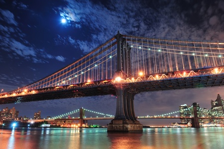 Brooklyn Bridge and Manhattan Bridge over East River at night with moon in New York City Manhattan with lights and reflections.のeditorial素材