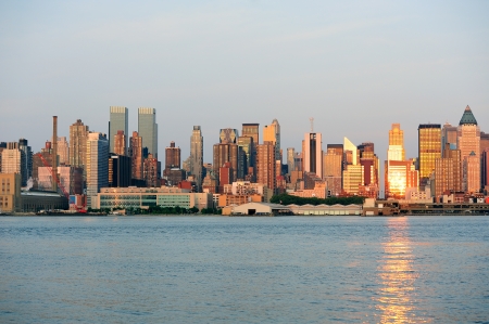 New York City Manhattan midtown skyline at sunset with reflection over skyscraper and river.の写真素材