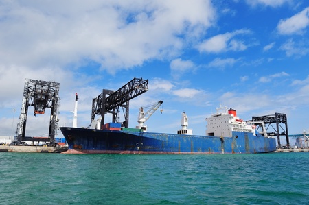 Cargo ship at Miami harbor with crane and blue sky over sea.の写真素材