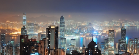 Hong Kong city skyline panorama at night with Victoria Harbor and skyscrapers illuminated by lights over water viewed from mountain top のeditorial素材