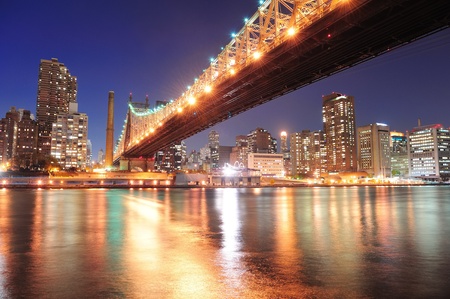 Queensboro Bridge over New York City East River at sunset with river reflections and midtown Manhattan skyline illuminated. のeditorial素材