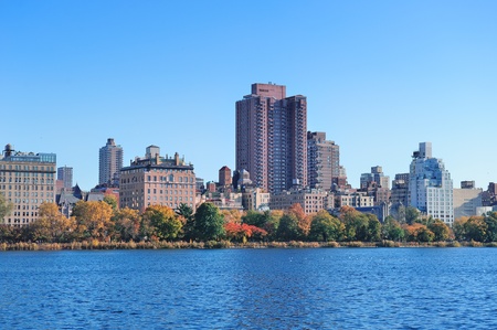 Central Park Autumn with New York City Manhattan Midtown skyline skyscrapers over lake with colorful foliage and clear blue sky.の写真素材