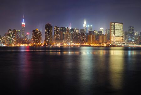 New York City Manhattan midtown panorama at night with skyscrapers illuminated over east riverの写真素材