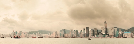Urban architecture in Hong Kong Victoria Harbor with city skyline and cloud in the day with yellow tone.の写真素材