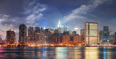 New York City Manhattan midtown panorama at dusk with skyscrapers illuminated over east riverのeditorial素材