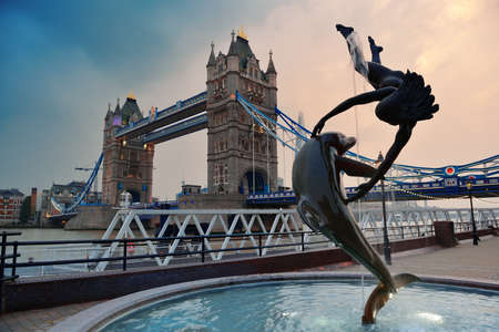 Tower Bridge and statue of a girl playing with dolphin in St Katharine docks in London.の写真素材