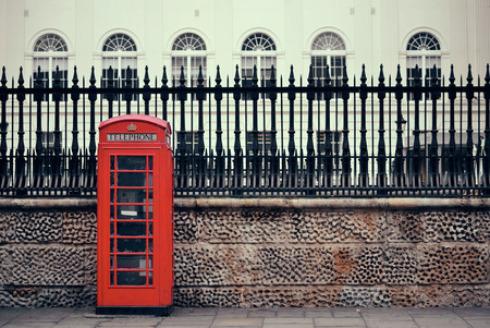 Red telephone box in street with historical architecture in London.