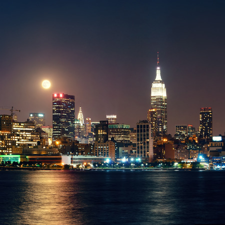 Moon rise over midtown Manhattan with city skyline at nightの写真素材