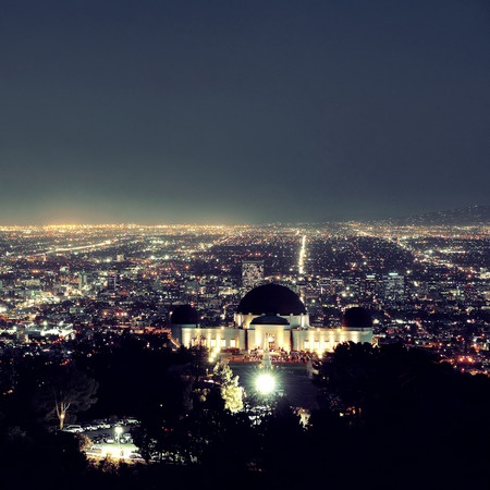 Los Angeles at night with urban buildings and Griffith Observatoryの写真素材