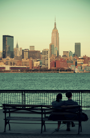 Couple rest on bench watching New York City skyscrapersの写真素材