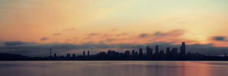 Seattle city skyline view over sea at sunrise with urban architecture.