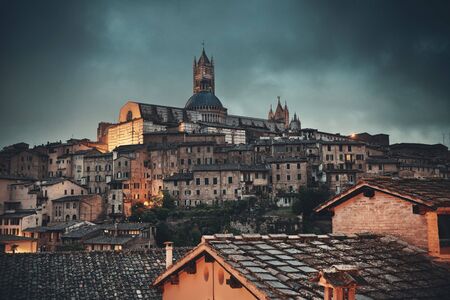 Medieval town skyline view with Siena Cathedral and historic buildings in Italy at nightの写真素材